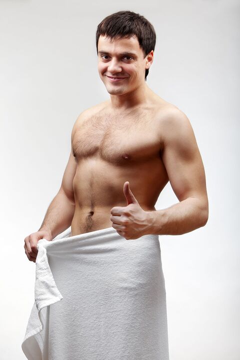 A man in a towel is pleased with the increased size of his penis
